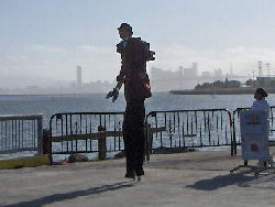 A stilt-wearing juggler performs in front of the San Francisco skyline.